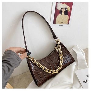 Detail of dark brown crocodile pattern underarm bag with thick gold chain decoration