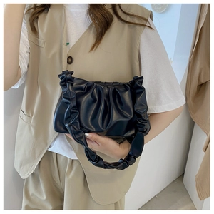 Close-up of black pleated cloud bag with soft textured handle and ruched design detail