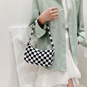 Classic black and white checkered canvas baguette bag worn on a shoulder over mint shirt