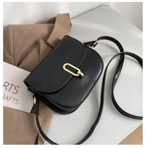 Detail der minimalistischen schwarzen Satteltasche mit mattem Leder und goldener Schließe