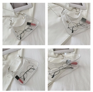 Detail view of transparent PVC hobo bag with silver zipper and lifestyle items inside