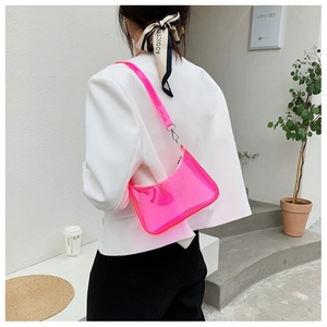 Hot pink transparent jelly baguette bag shown over the shoulder with white blazer