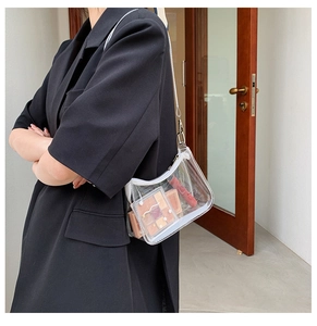 On-shoulder view of a transparent PVC jelly bag with cosmetics and white zipper detail