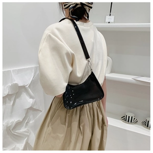 Glossy black patent leather underarm bag shown on model with minimalist retro style