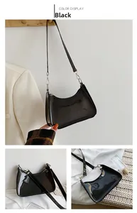 Detail of glossy black patent leather underarm bag with silver metal buckles and sleek finish