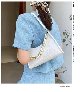 Detail of white crocodile pattern baguette bag with stylish gold and white thick chain strap