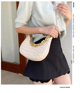 Detail of off-white crescent bag with crocodile texture and gold chunky chain strap