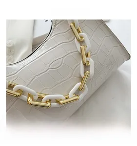 Detail of white crocodile texture leather handbag featuring a stylish chunky resin chain