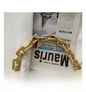 Close-up of chunky gold-tone metal chain handle on a textured crocodile crescent handbag