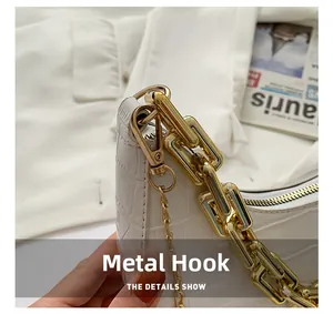 Detail of white crocodile-patterned leather bag featuring gold hardware and rotating hook