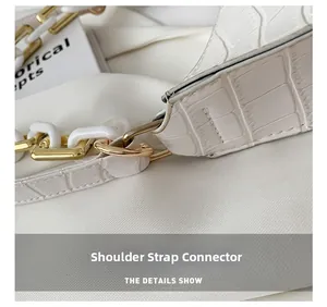 Detail of white crocodile embossed leather bag with gold buckle and resin chain strap
