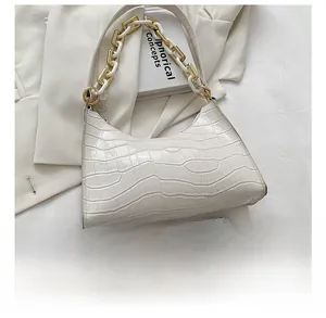Detail of white crocodile pattern shoulder bag with a gold and white chunky chain strap