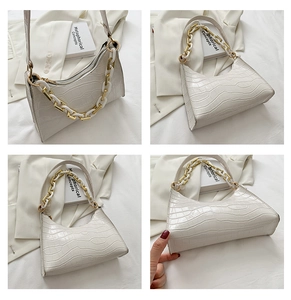 Detail view of white croc-embossed baguette bag with stylish gold and white chain strap