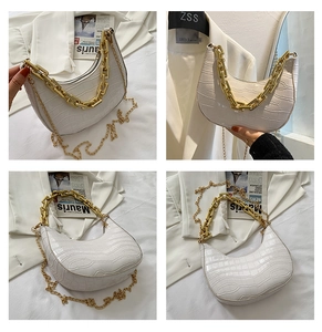 Detail view of white croc-embossed crescent bag with chunky gold chain and slim strap