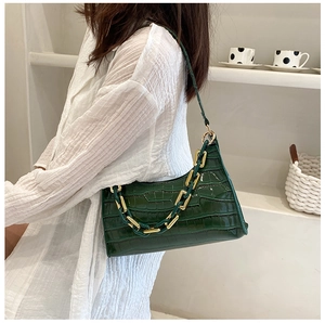 Detail of dark green crocodile pattern bag featuring thick gold chain and leather strap