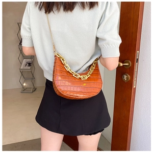 Close-up of brown crocodile texture handbag with chunky gold chain detail