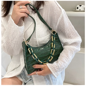 Detail of dark green crocodile pattern hobo bag with bold gold chain and shoulder strap