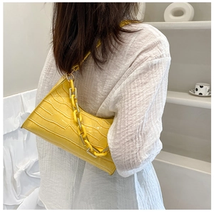 Detail view of bright yellow crocodile embossed hobo bag with thick resin chain strap