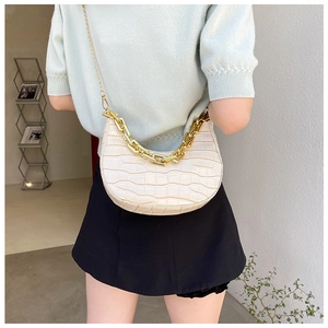 Detail of cream croissant bag with gold chain strap and crocodile embossed texture
