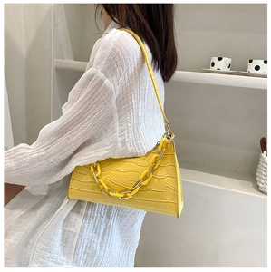 Detail of yellow crocodile pattern baguette bag with chunky resin and metal chain strap