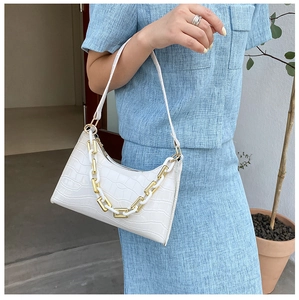 White baguette bag with crocodile texture and chunky chain detail worn by a model
