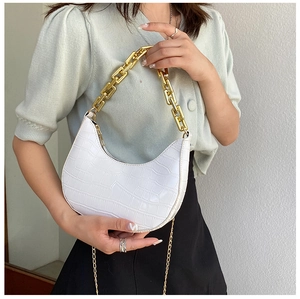 Detail of white crocodile pattern crescent bag with chunky gold chain and metallic strap