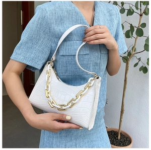 Detail of white crocodile texture underarm bag with decorative gold and white chunky chain