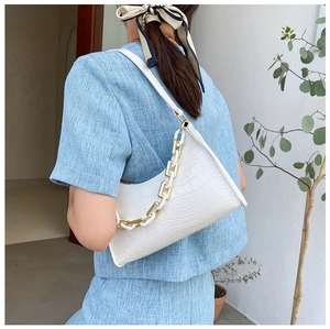 Detailed view of white crocodile pattern shoulder bag with decorative thick gold chain