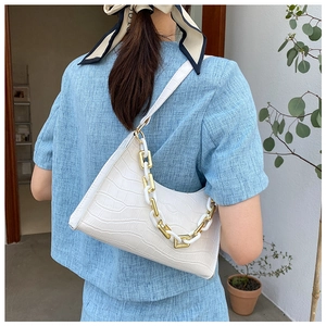 Detail view of white crocodile texture handbag with gold and white chunky chain strap