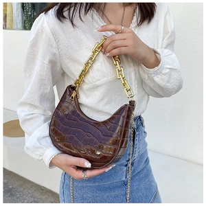 Detail of dark brown crocodile embossed crescent bag with thick gold chain strap