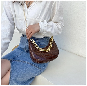 Detail of dark brown hobo bag with crocodile texture and thick golden chain handle