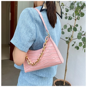 Detailed close-up of pink crocodile-embossed baguette bag with stylish gold chain strap