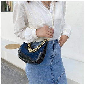 Detail of black crocodile texture crescent bag with chunky gold chain and metallic strap