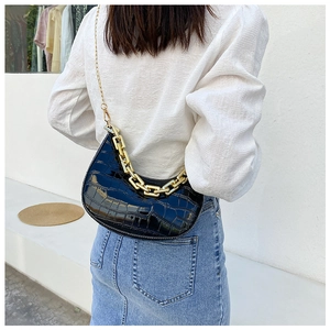 Detail of black crocodile texture crescent bag with chunky gold chain strap and glossy finish