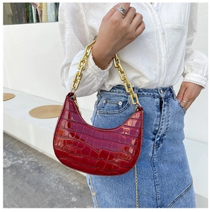 Detail of dark red crescent bag featuring textured crocodile pattern and bold gold chain