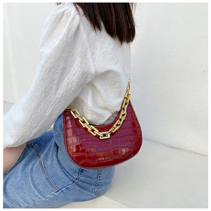 Detail of burgundy crocodile-embossed crescent bag with chunky gold chain strap