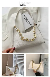 Detail of white crocodile embossed underarm bag with decorative gold chain strap