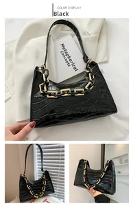 Detail of black faux crocodile leather bag with bold gold and black chain decoration