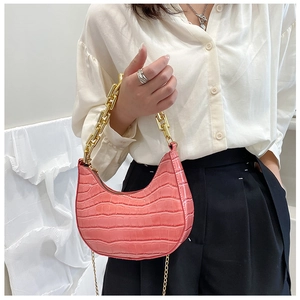 Close-up of pink crocodile pattern hobo bag with thick gold chain strap on shoulder