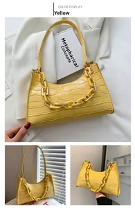 Detail of yellow baguette bag featuring faux crocodile texture and chunky acrylic chain