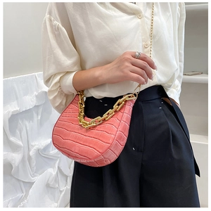 Detail of coral pink crocodile texture half-moon bag with chunky gold chain