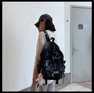 Détail d'un sac à dos noir avec imprimés graffiti et charmant pendentif canard