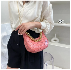 Pink crocodile pattern crescent bag with chunky gold chain detail on minimalist background