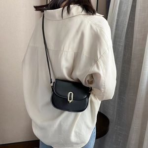 Minimalistische schwarze Leder-Satteltasche mit goldener U-Schnalle an einem Modell