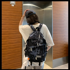 Sac à dos noir style urbain avec imprimé blanc et pendentif canard porté par un mannequin