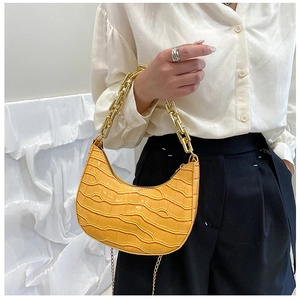Detail of yellow crocodile pattern crescent bag with chunky gold chain strap
