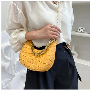 Detail of yellow crocodile pattern crescent bag with bold gold chain and metallic strap
