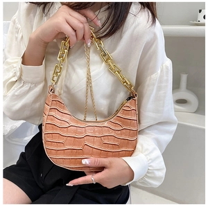 Close-up of caramel crocodile pattern crescent bag with chunky gold chain on model