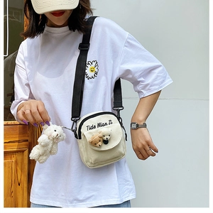 Beige canvas crossbody bag featuring cute bear heads and a plush bear keychain charm