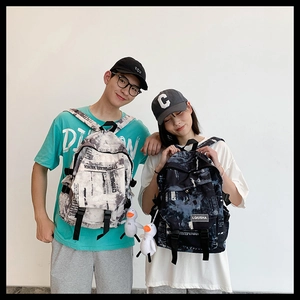 Détail de sacs à dos pour couple avec motifs camo, étiquettes et breloques canard